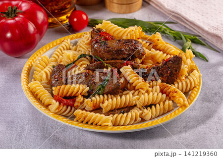 Pasta with grilled meat and herbs on yellow plate Pasta with grilled meat and herbs on yellow plate 141219360