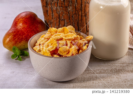 Corn flakes cereal bowl with fresh pear and milk bottle on rustic wood Corn flakes cereal bowl with fresh pear and milk bottle on rustic wood 141219380
