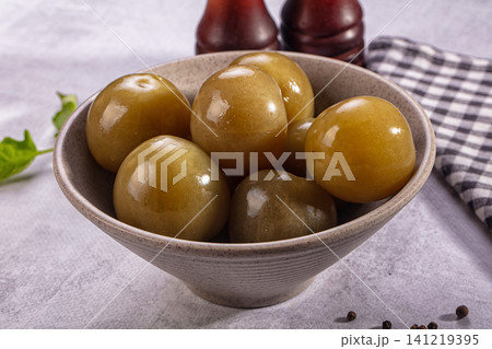 Green olives in ceramic bowl with checkered napkin and pepper mills Green olives in ceramic bowl with checkered napkin and pepper mills 141219395