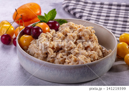 Oatmeal bowl with fresh cherries and mint on textured surface Oatmeal bowl with fresh cherries and mint on textured surface 141219399