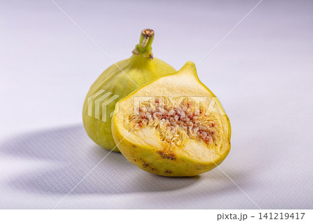 Fresh fig sliced open showing juicy interior on white textured surface Fresh fig sliced open showing juicy interior on white textured surface 141219417