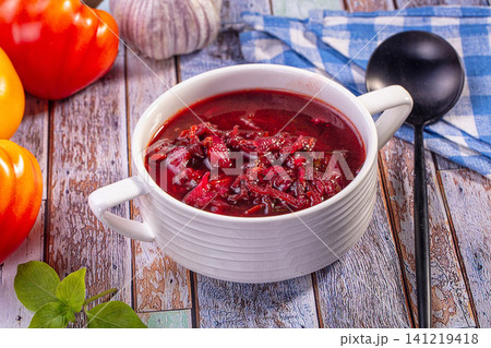 Borsch soup in white bowl with red peppers and garlic on rustic wooden table Borsch soup in white bowl with red peppers and garlic on rustic wooden table 141219418