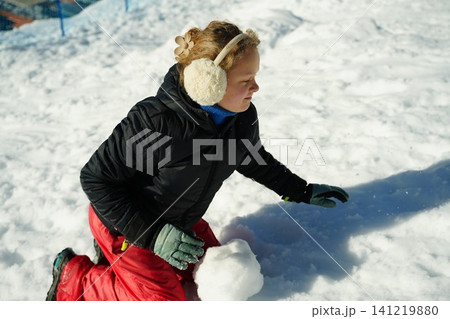 Child Playing in Snow with Joyful Expression Child Playing in Snow with Joyful Expression 141219880