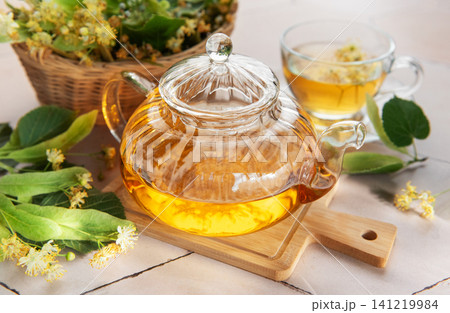 Linden tea brewing in glass teapot with lime blossom Linden tea brewing in glass teapot with lime blossom 141219984