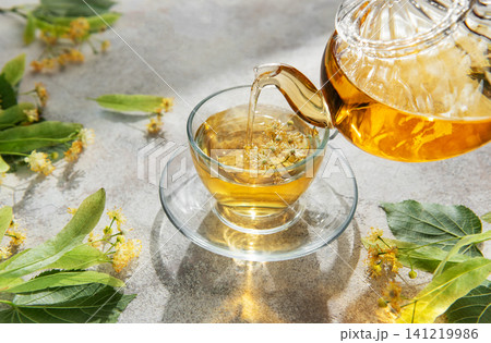 Pouring linden tea into glass cup for relaxation Pouring linden tea into glass cup for relaxation 141219986