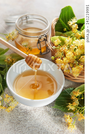 Honey dripping into bowl with linden flowers 141219991