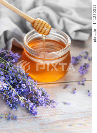 Honey dripping from wooden dipper with fresh lavender Honey dripping from wooden dipper with fresh lavender 141220015