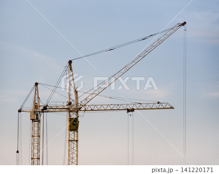 Construction tower cranes against a clear sky with large copy space. Minimalistic industrial scene representing building, development, engineering and urban growth. Construction tower cranes against a clear sky with large copy space. Minimalistic industrial scene representing building, development, engineering and urban growth. 141220171