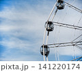 Volgograd, Russia - 05.23.2023: Ferris wheel gondolas suspended in mid-air. Amusement park ride capsules against blue sky with clouds 141220174