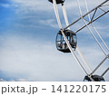 Volgograd, Russia - 05.23.2023 Ferris wheel gondola cabin in motion at amusement park. High-angle view of circular observation ride against blue sky backdrop. 141220175