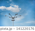 Modern street light pole against a blue sky with soft clouds and large copy space. Minimalist urban scene with a bird silhouette, representing city infrastructure, technology and public lighting. 141220176