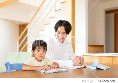 リビングで勉強をする小学生の男の子と父親 リビングで勉強をする小学生の男の子と父親 141220726