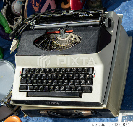XALO, SPAIN - JUNE 20, 2026.A vintage Imperial mechanical typewriter sits on a table at a local flea market. Surrounding items include various retro collectibles, showing the charm of past decades and XALO, SPAIN - JUNE 20, 2026.A vintage Imperial mechanical typewriter sits on a table at a local flea market. Surrounding items include various retro collectibles, showing the charm of past decades and 141221074