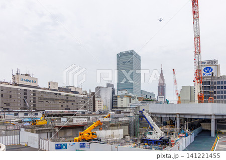 新宿駅西口の再開発工事と上空を飛ぶ旅客機 141221455