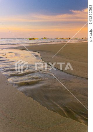 Sunset beach in Indonesia with golden waves and pristine white sand capturing tropical beauty and serene coastal atmosphere 141222562