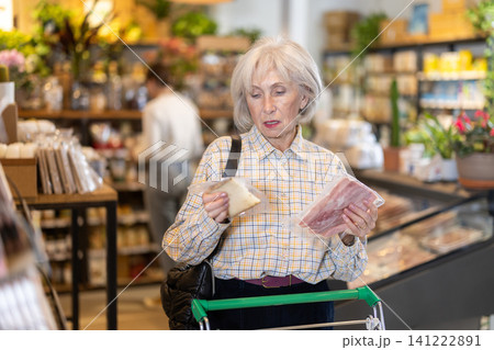 Elderly woman choosing cheese and bacon in grocery supermarket 141222891