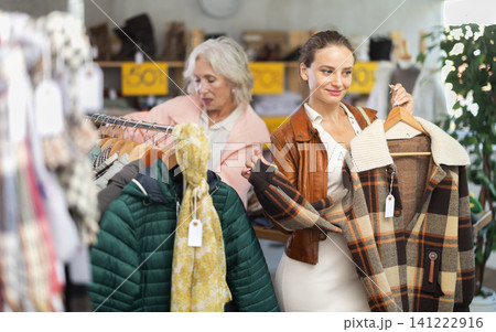 woman, together with a mature woman, chooses outerwear woman, together with a mature woman, chooses outerwear 141222916