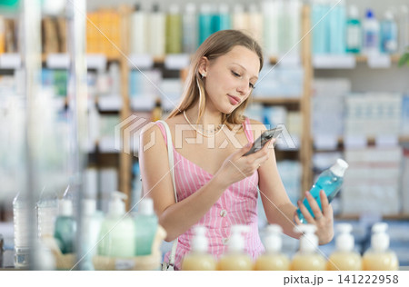 Blonde woman scanning on mobile bottle with rinse aid Blonde woman scanning on mobile bottle with rinse aid 141222958