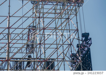 Detail of metal scaffolding and truss rigging with suspended speakers and lighting for an outdoor concert stage against a blue sky. High quality photo 141223037