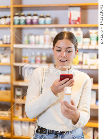Girl get acquainted with dietary supplement, scan QR code, take reading label using phone camera Girl get acquainted with dietary supplement, scan QR code, take reading label using phone camera 141223041