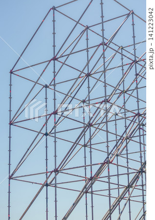 Metal scaffolding poles and diagonal braces forming a minimal abstract geometric grid pattern against a clear blue sky in vertical format. High quality photo Metal scaffolding poles and diagonal braces forming a minimal abstract geometric grid pattern against a clear blue sky in vertical format. High quality photo 141223042
