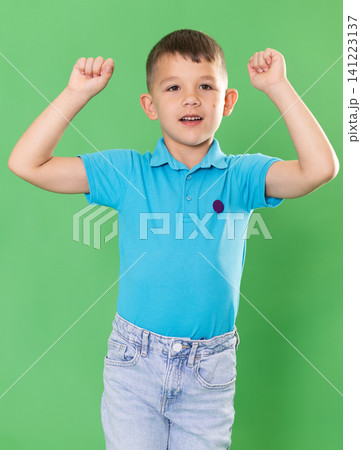 Smiling boy in blue jeans expressing delight and ena on green background Smiling boy in blue jeans expressing delight and ena on green background 141223137