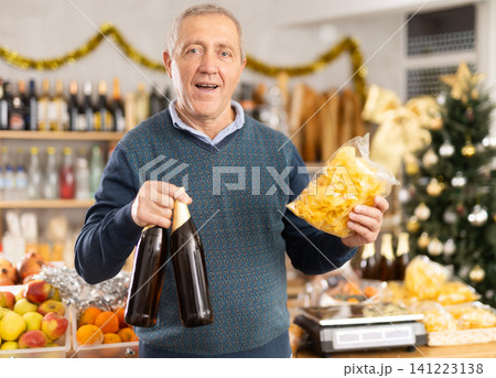 Elderly man chooses beer and chips at grocery store Elderly man chooses beer and chips at grocery store 141223138