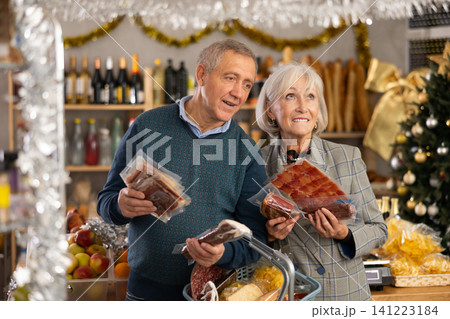 Elderly couple considering buying hamon and vacuumed slicing smoked sausage 141223184