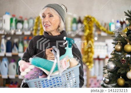 Elderly woman chooses household chemicals in decorated store Elderly woman chooses household chemicals in decorated store 141223215