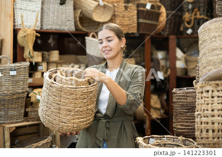 Girl looks at wicker basket in store. 141223301