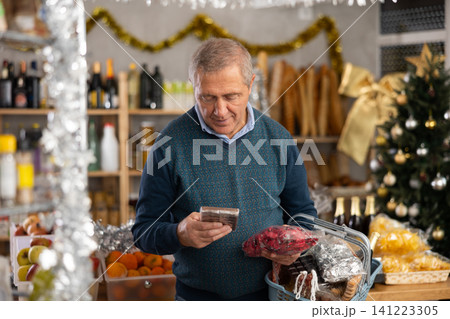 Elderly man chooses chocolates and candies in grocery 141223305
