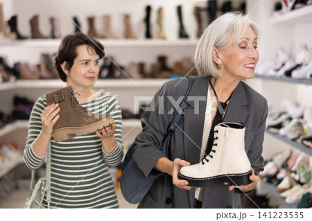 Adult and elderly women choosing boots in store Adult and elderly women choosing boots in store 141223535