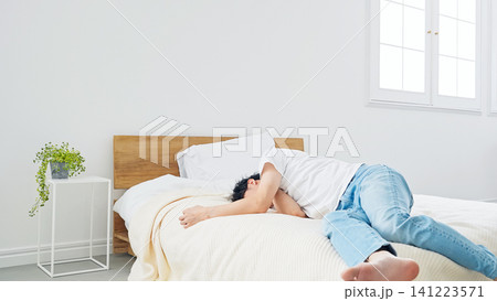 ベッドに寝転がる男性。寝不足、不眠症、落ち込む、がっかり、悩む、ストレス、昼寝、疲労、不安、寝坊 ベッドに寝転がる男性。寝不足、不眠症、落ち込む、がっかり、悩む、ストレス、昼寝、疲労、不安、寝坊 141223571
