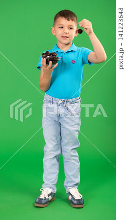 Boy in blue clothes happily eats ripe cherries on green background Boy in blue clothes happily eats ripe cherries on green background 141223648