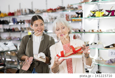 Elderly woman and young woman choosing sandals in shoe store Elderly woman and young woman choosing sandals in shoe store 141223710
