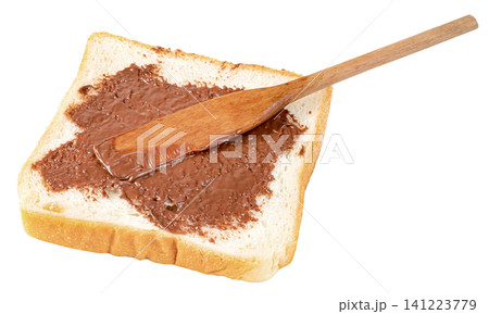 A slice of white toast bread with sweet chocolate hazelnut spread being applied using a wooden spatula. Isolated. Perfect for breakfast or snack concepts. A slice of white toast bread with sweet chocolate hazelnut spread being applied using a wooden spatula. Isolated. Perfect for breakfast or snack concepts. 141223779