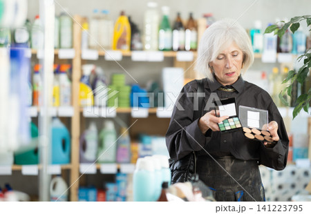 Elderly woman choosing cosmetics in household chemicals store Elderly woman choosing cosmetics in household chemicals store 141223795