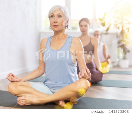 Elderly woman doing yoga in group in studio Elderly woman doing yoga in group in studio 141223808