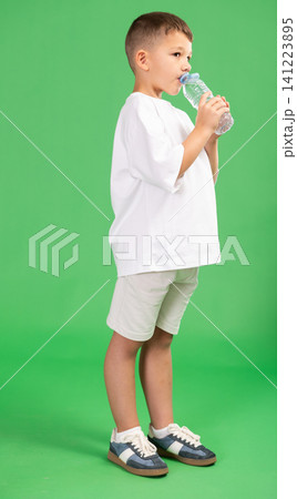 Boy with bottle of water quenches thirst 141223895