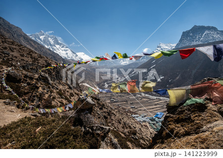 Prayer flags hanging on the viewpoint in Dingboche village, Nepal. Prayer flags at a viewpoint symbolize peace, compassion, and good fortune. Prayer flags hanging on the viewpoint in Dingboche village, Nepal. Prayer flags at a viewpoint symbolize peace, compassion, and good fortune. 141223999