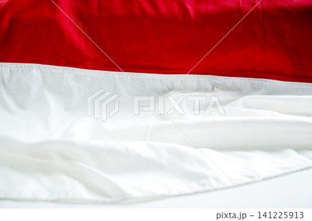Close-up of red and white draped fabrics representing the Indonesian flag. Textured abstract background with soft folds for patriotic themes, national day, and celebrations 141225913