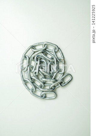 A heavy-duty steel chain coiled in a spiral pattern on a plain background, representing strength, connection, and security A heavy-duty steel chain coiled in a spiral pattern on a plain background, representing strength, connection, and security 141225925
