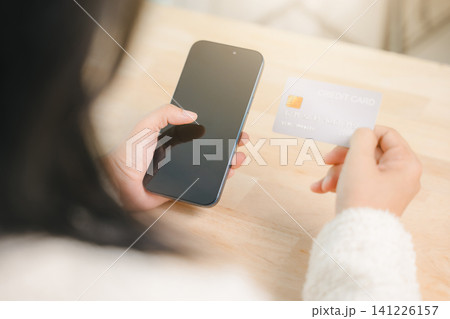 Paying and shopping with credit card and mobile phone in computer home business concept, woman holding smartphone and credit card for online payment and ecommerce transfer 141226157