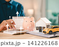 Real estate investment growth management and property asset invest concept shows businessman using calculator next to piggy bank and house model beside car under rising arrows 141226168