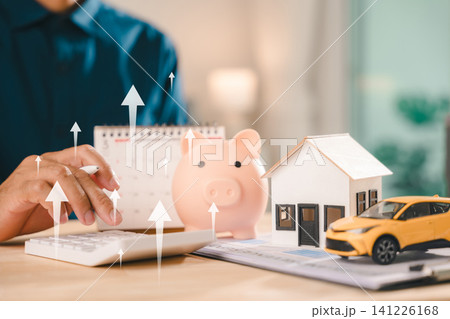 Real estate investment growth management and property asset invest concept shows businessman using calculator next to piggy bank and house model beside car under rising arrows Real estate investment growth management and property asset invest concept shows businessman using calculator next to piggy bank and house model beside car under rising arrows 141226168