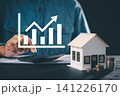 Real estate investment growth management and property asset invest planning shows hand using calculator next to small house model, stacks of coins, growing business graphic chart 141226170