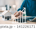 Real estate investment growth management and property asset invest concept shows businessman using calculator next to house model and laptop under rising financial chart 141226171