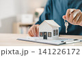 Real estate home purchase property ownership mortgage investment house where residential contract housing deals show agent handing over keys near miniature house model on wooden desk 141226172