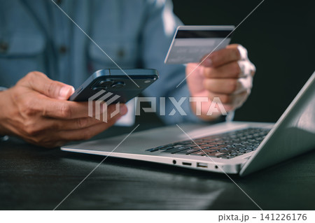 Man uses smartphone, digital, display, cyber, security, online, shopping, protection while paying with credit card on laptop, completing safe mobile payment, ensuring secure internet networking Man uses smartphone, digital, display, cyber, security, online, shopping, protection while paying with credit card on laptop, completing safe mobile payment, ensuring secure internet networking 141226176