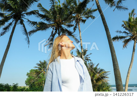 Person smiling under palm trees by the beach in Bali Person smiling under palm trees by the beach in Bali 141226317